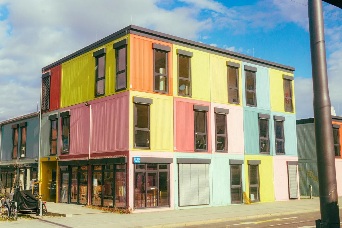 Edificio modular de tres plantas, con fachada de paneles y ventanas en hilera.